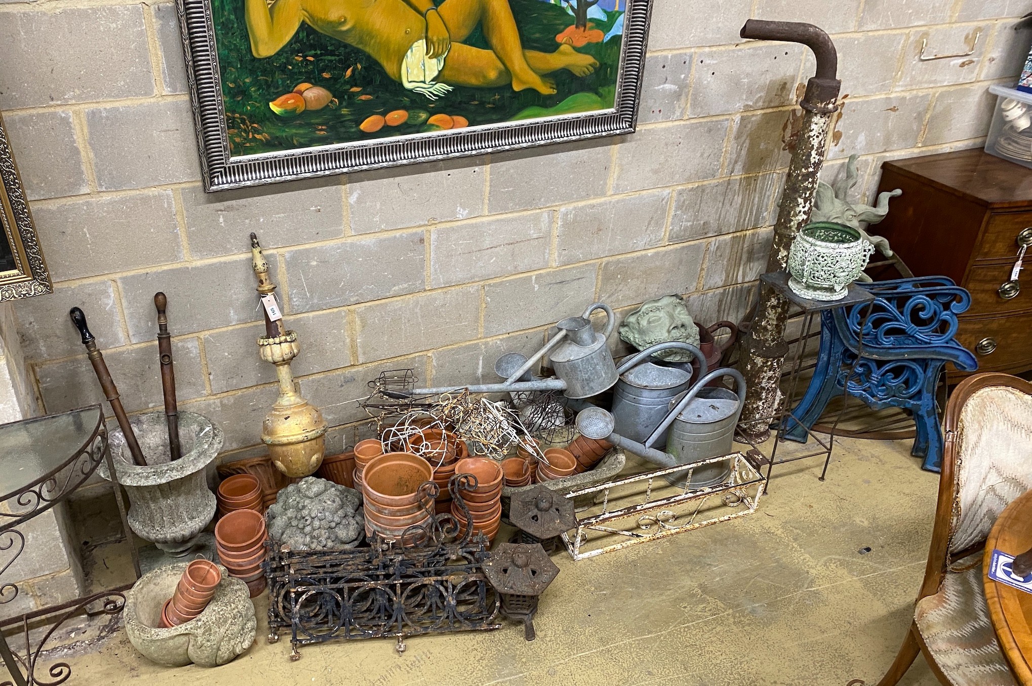 A large quantity of assorted garden ornaments, terracotta pots, galvanised watering cans, bench ends, etc.